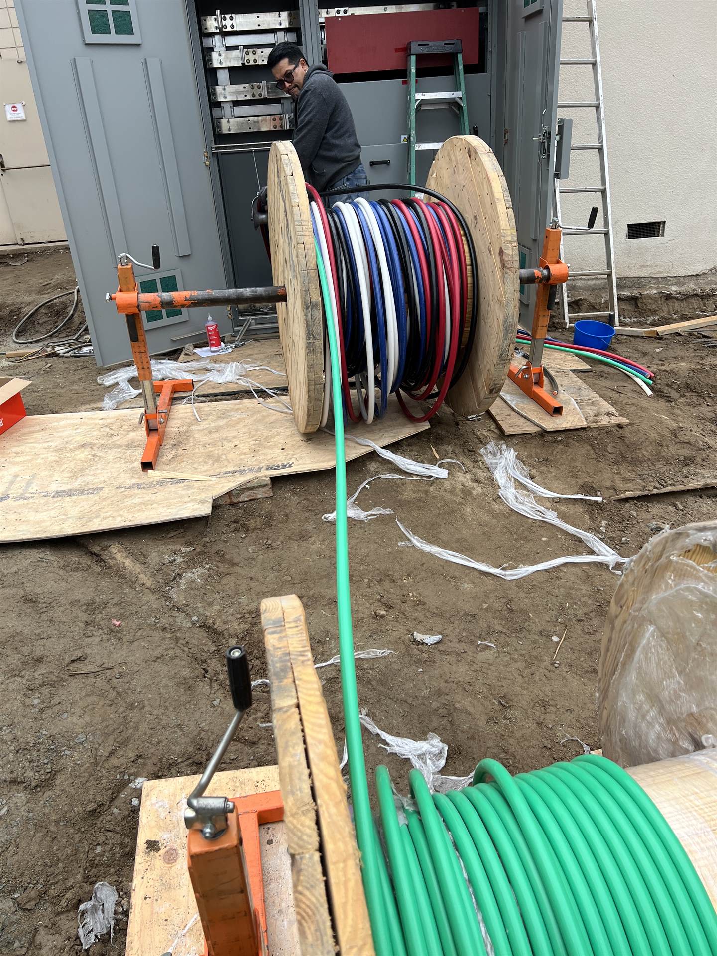 Electrician pulling wire from cable reels on a commercial job site